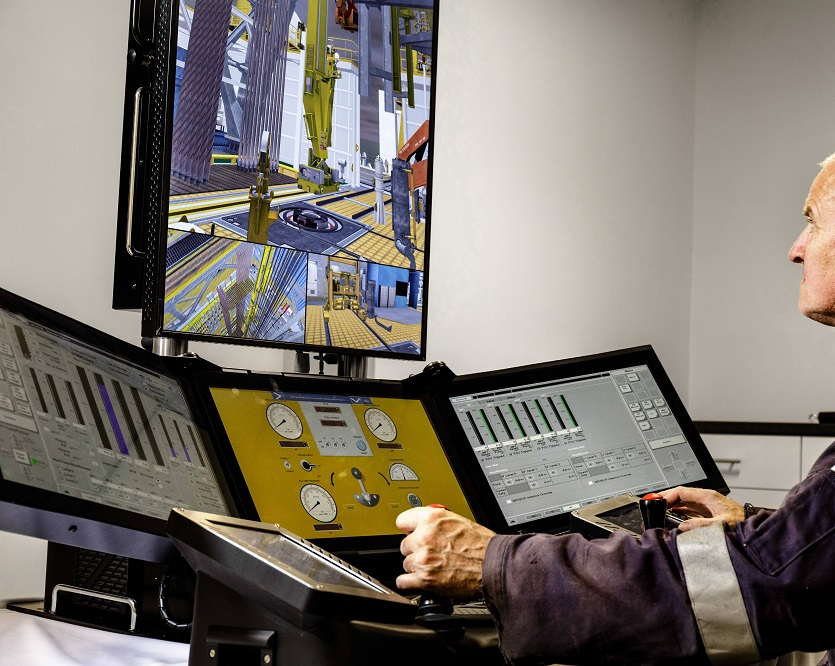 A person using a sophisticated control panel with multiple screens, operating and monitoring various gauges and graphical displays, likely in an industrial or simulation setting.